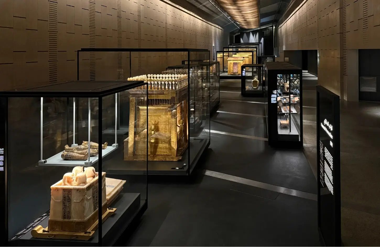 Golden artifacts and ancient royal burial treasures displayed in glass cases inside the Tutankhamun gallery at the Grand Egyptian Museum.